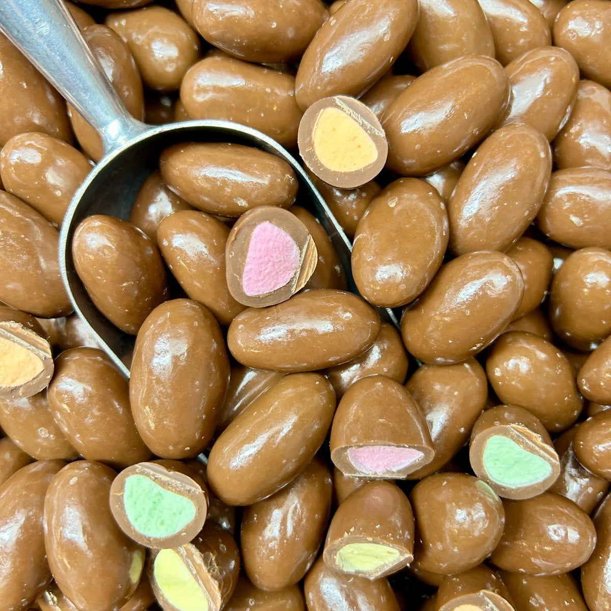 Close-up of Clinkers candies and a metal scoop, with cut pieces showing colourful centres.