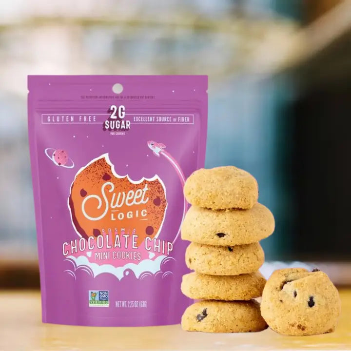 A purple bag of Sweet Logic Chocolate Chip Mini Cookies stands on a light surface with several golden-brown cookies stacked and placed beside it. The package shows the brand name Sweet Logic and highlights gluten free, 2g sugar, and excellent source of fiber.