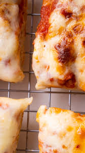 Close-up of several baked pizza slices cooling on a metal wire rack.