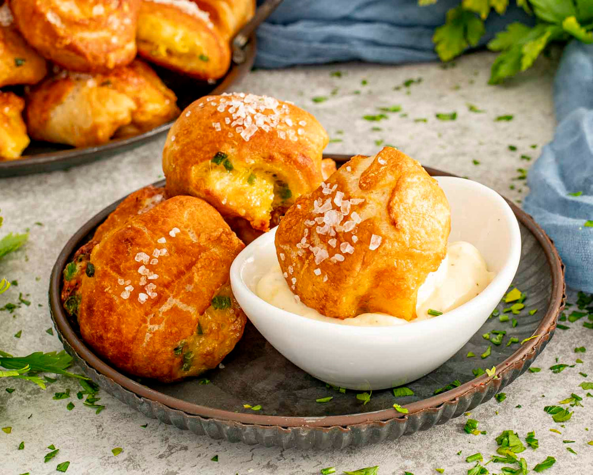 Golden salted pretzel bites beside a bowl of white dipping sauce.