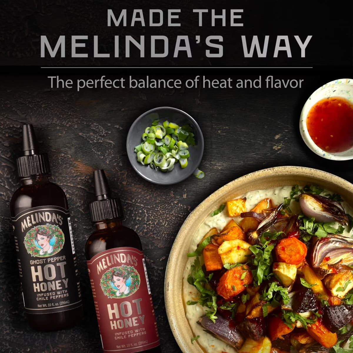 Melinda’s Classic and Ghost Pepper Hot Honey bottles beside a bowl of roasted vegetables
