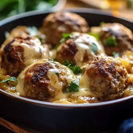 Browned meatballs in creamy sauce, garnished with chopped parsley.