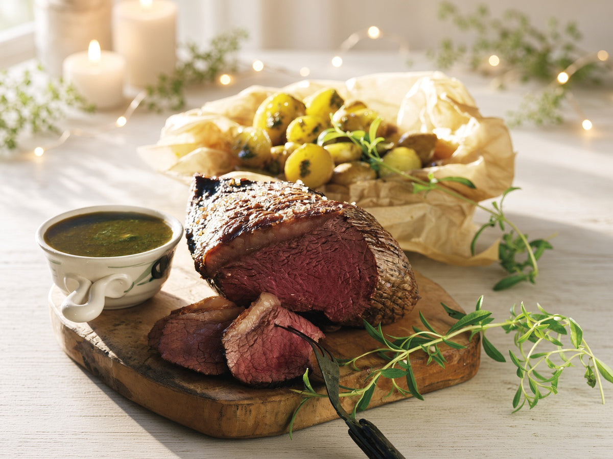  roast with a sauce bowl on the left and potatoes behind it, is still blank. Use: Culotte beef roast sliced on a wooden board, with potatoes, herbs, and sauce alongside