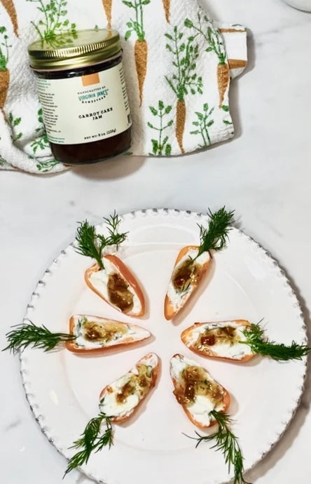 a white plate of appetizer canapes topped with the cheese spread and garnished with dill on a white marble surface.