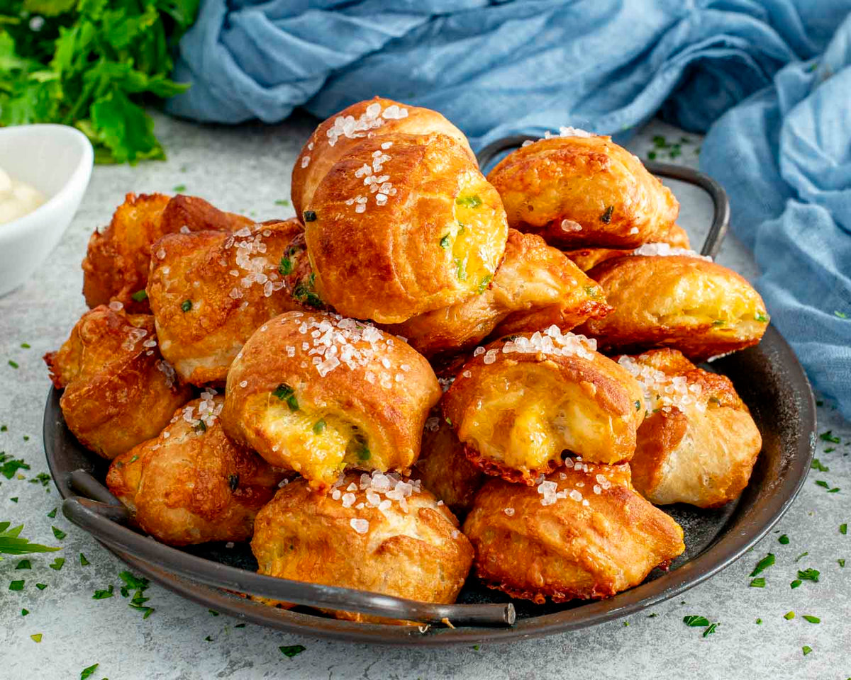 Golden salted pretzel bites piled on a dark serving plate.