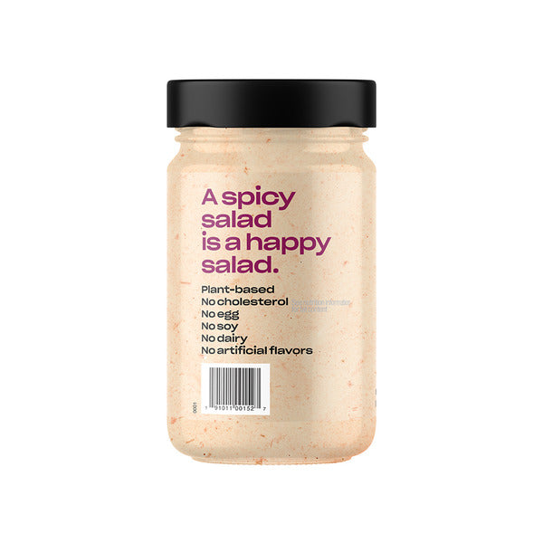 A jar of plant-based creamy salad dressing with a black lid and a light beige-pink product inside, featuring purple and black text on the label, set against a plain white background.