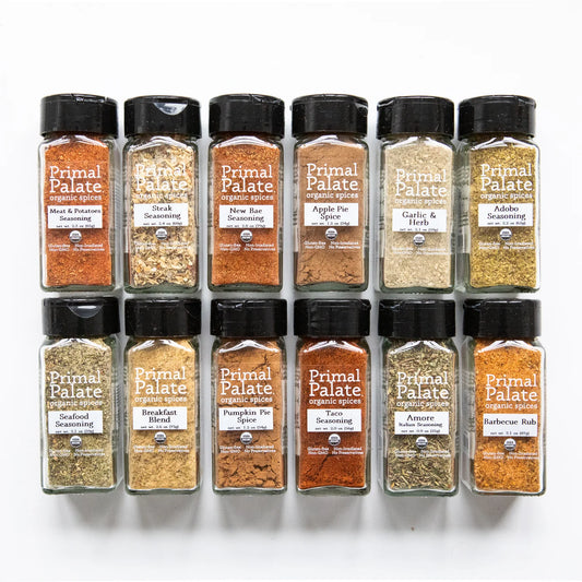 A 12-pack set of Primal Palate Seasoning spice bottles arranged in a 2x6 grid on a white background. The set includes various spices such as Meat & Potato Seasoning, Steak Seasoning, New Rice Seasoning, Apple Pie Spice, Garlic & Herb Seasoning, Addable Seasoning, Seafood & Potato Seasoning, Breakfast Blend, Pumpkin Pie Spice, Taco Seasoning, Avocado Seasoning, and Barbecue Rub.
