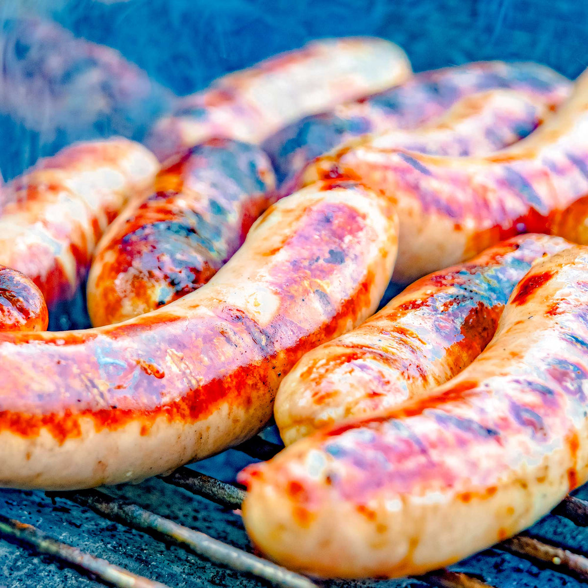 Grilled sausages on a barbecue grill with a blue background