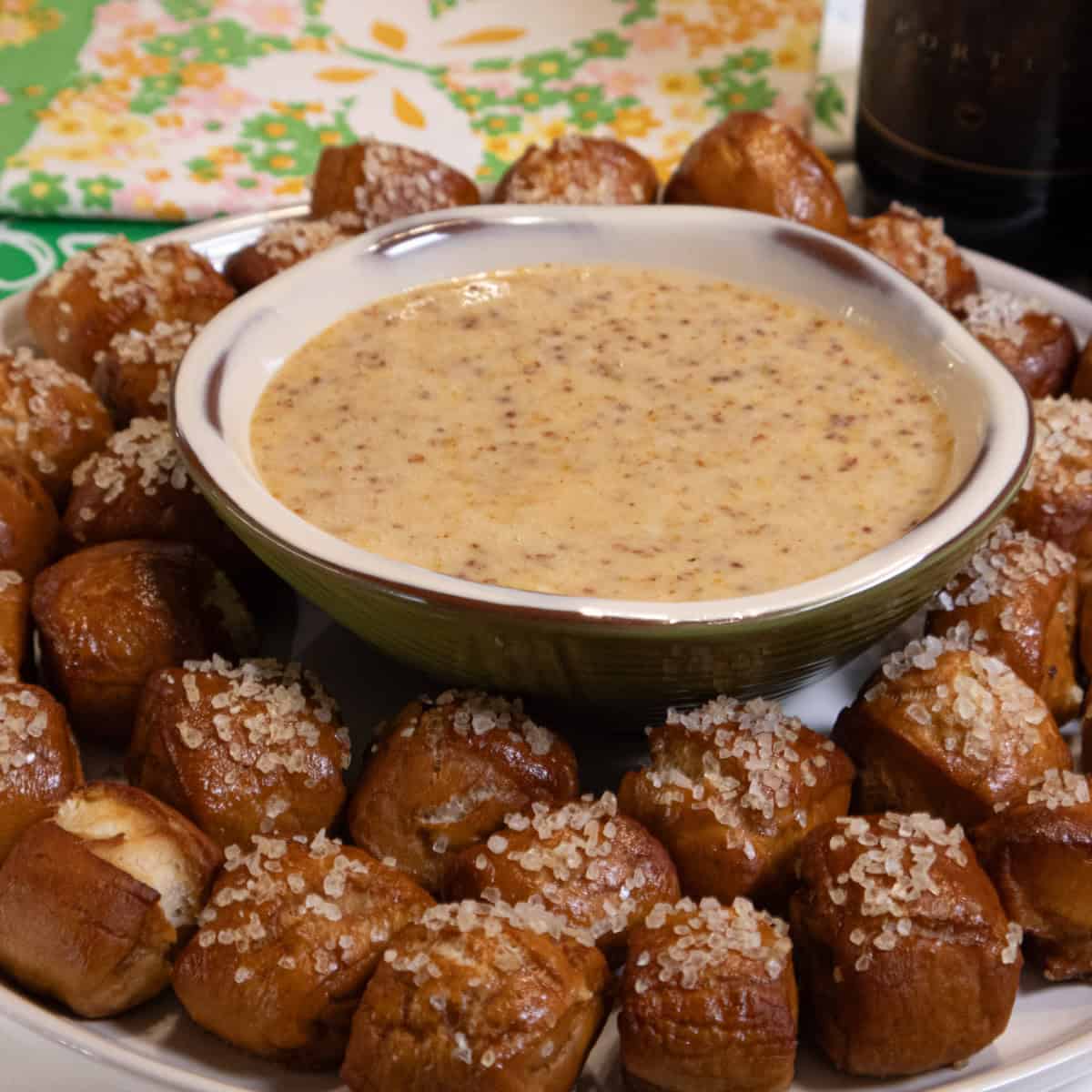 Salted pretzel bites surrounding a metal bowl of creamy dipping sauce.