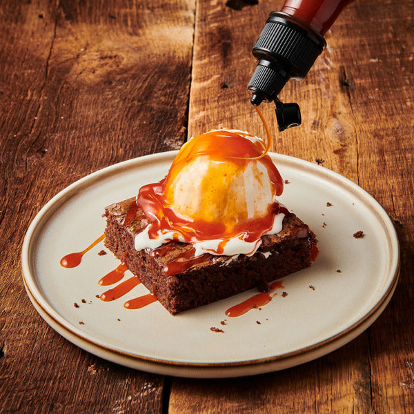 Hot honey sauce drizzled over vanilla ice cream on a chocolate brownie

