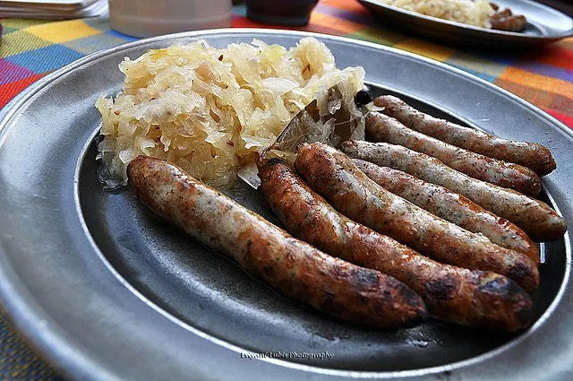 Seven browned bratwurst links served with sliced potatoes and mustard.