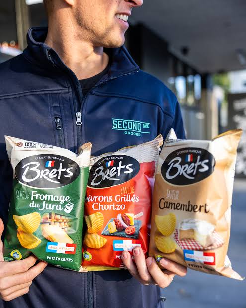 Person holding Brets Jura Cheese, Grilled Peppers and Chorizo, and Camembert potato-chip bags
