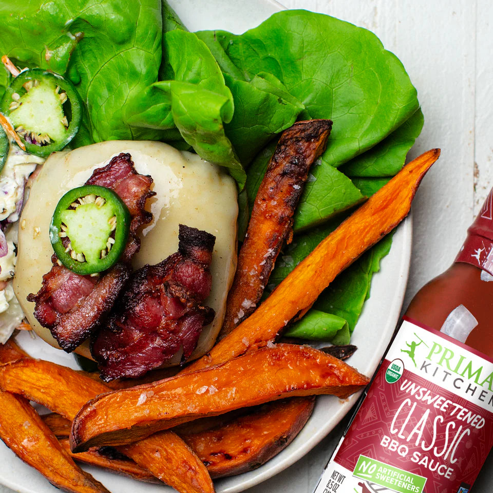 Plated dish with burger, sweet potato fries, and Primal Kitchen BBQ sauce