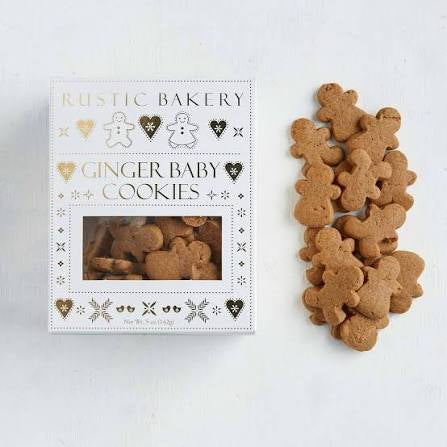 A box of Rustic Bakery Ginger Baby Cookies next to a pile of small gingerbread-shaped cookies on a white background.