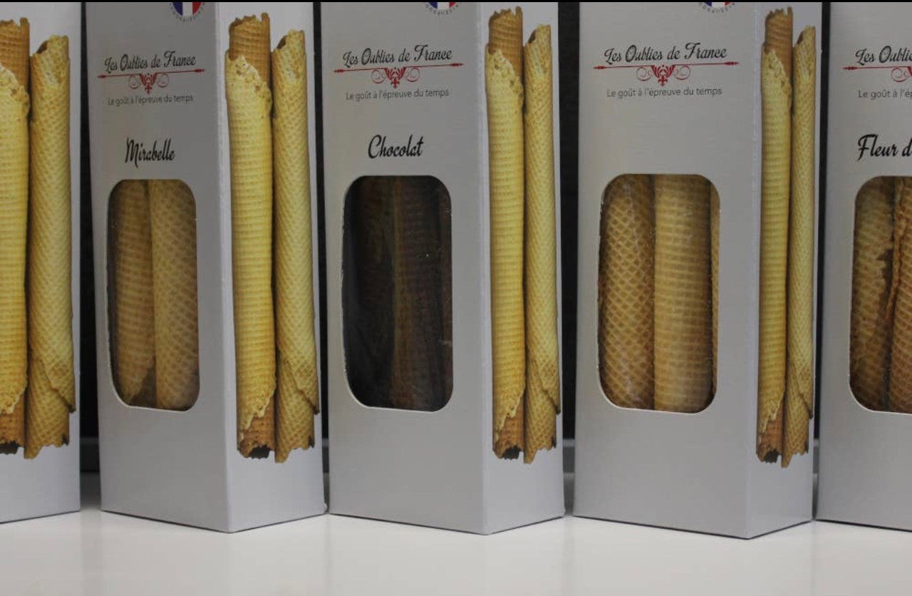 Several tall white boxes of French vanilla waffle cones lined up on a white surface. The boxes feature printed images of golden-brown waffle cones and labels reading 'Les Outils de France' and product names like 'Mirabelle' and 'Chocolat'.