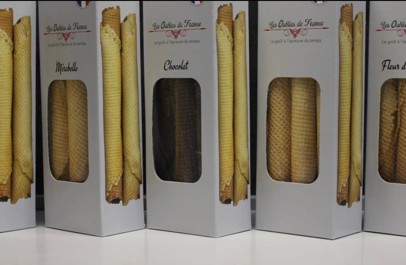 Several tall white boxes of French vanilla waffle cones lined up on a white surface. The boxes feature printed images of golden-brown waffle cones and labels reading 'Les Outils de France' and product names like 'Mirabelle' and 'Chocolat'.