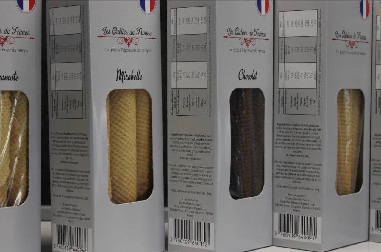 Several tall white boxes of French pastry arranged side by side, with clear windows showing filled pastries inside. Visible text includes 'Les Outils de France' and product names such as 'Michelette' and 'Chocolat'.