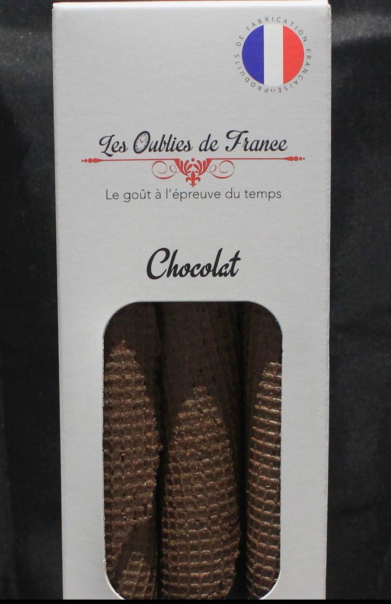 A white rectangular box of chocolate canapes from 'Les Outils de Français', featuring a French flag emblem and a clear window displaying three brown, ribbed chocolate canapes.