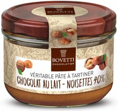 A glass jar of Bovetti Chocolatier tartiner paste filled with hazelnut chocolate, featuring a brown lid and a beige patterned label with hazelnut illustrations.