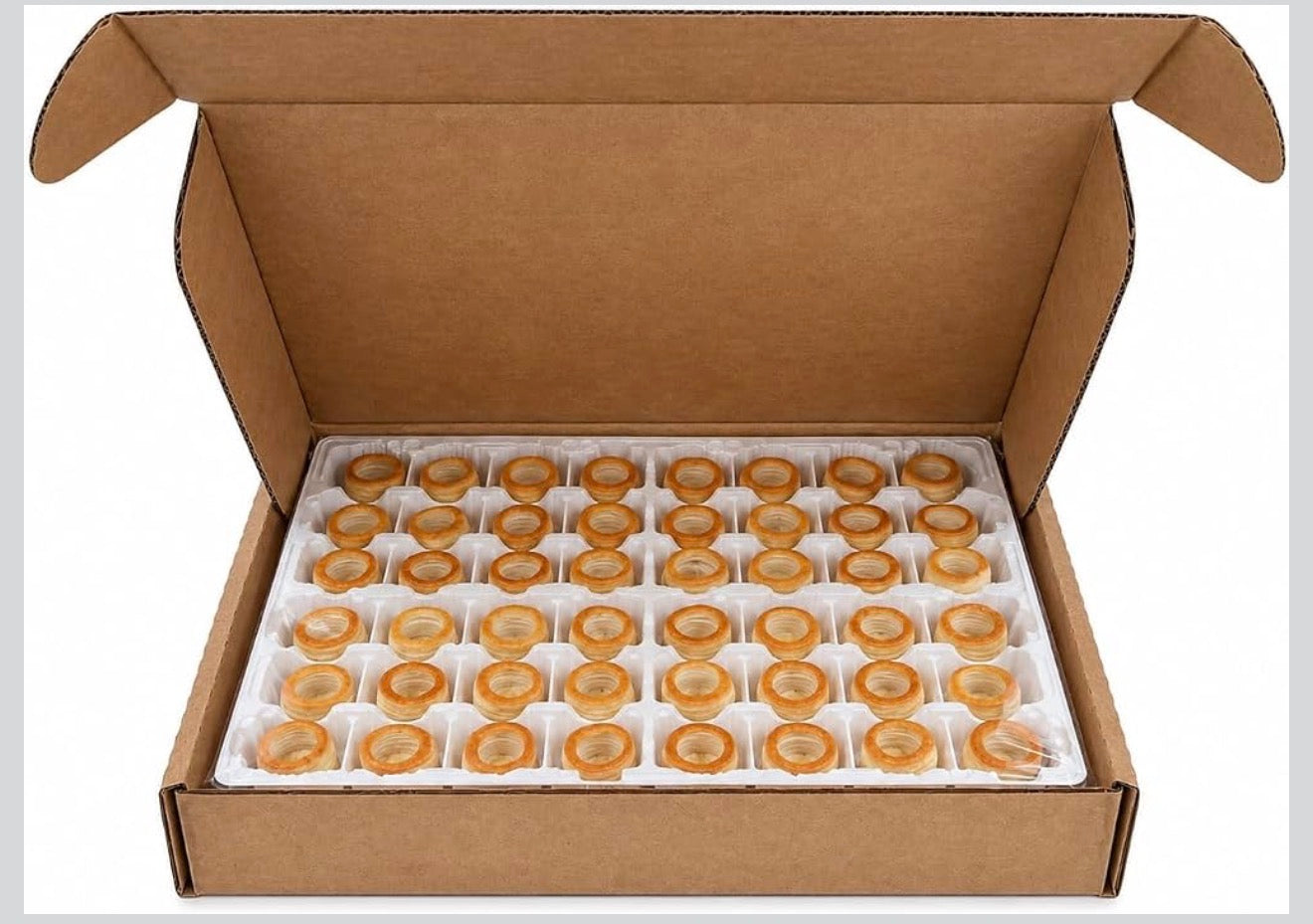 An open brown cardboard box containing multiple small round amber-orange items arranged in a white foam tray, photographed on a plain white background.