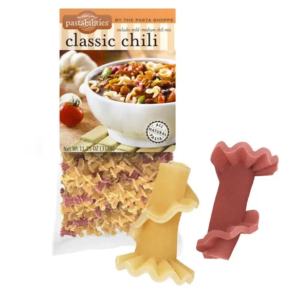 Pastabilities Classic Chili pasta in its packaging, shown alongside two loose pieces of the curly chili-shaped pasta: one yellow and one reddish pink, on a plain white background.