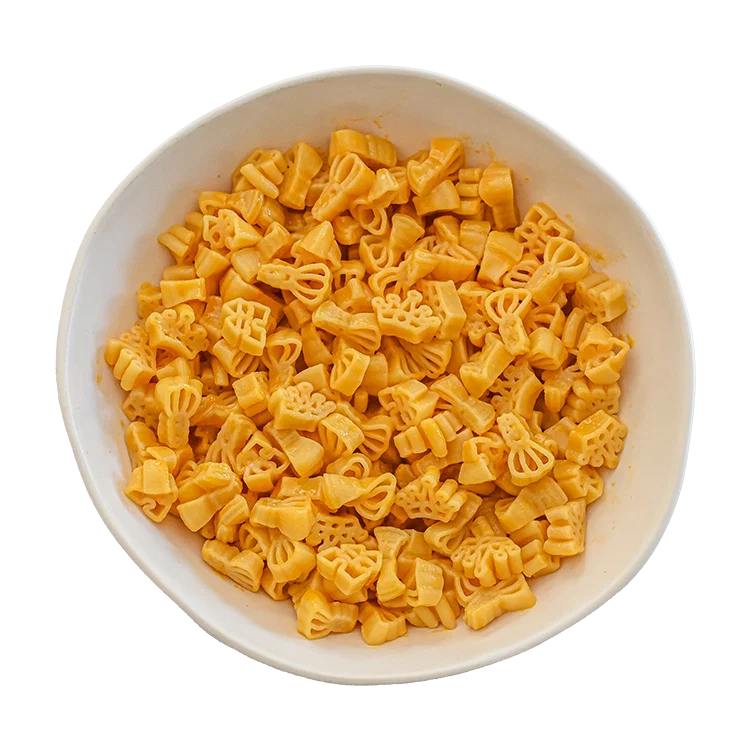 Yellow novelty macaroni pasta shaped like small crowns, shown piled in a white bowl against a white background.