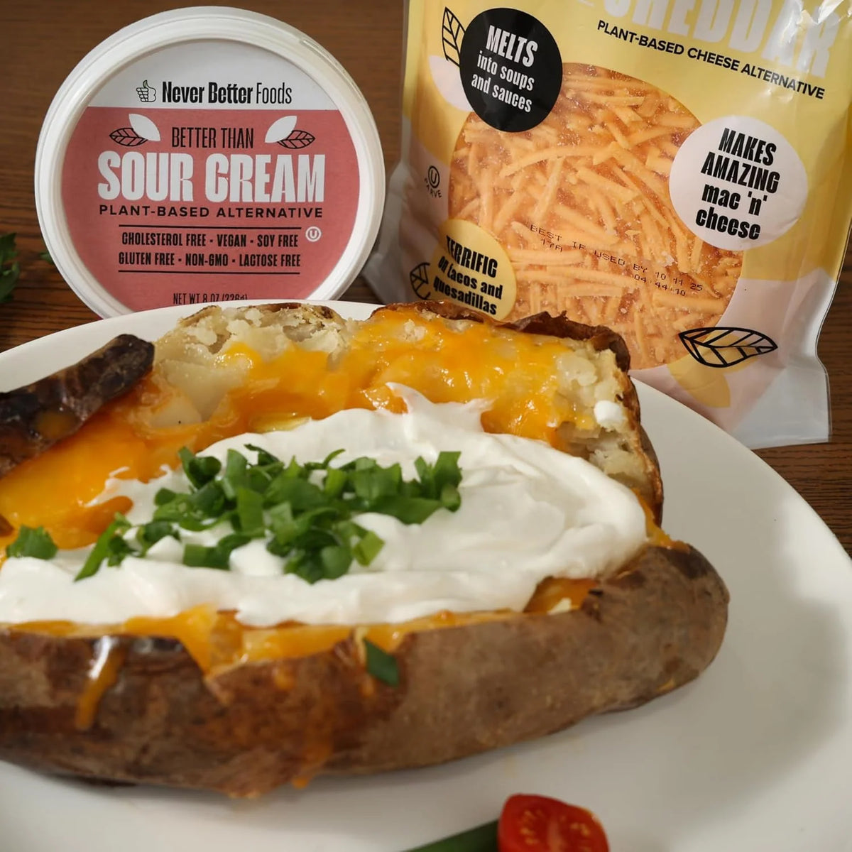 Baked potato topped with sour cream, with Never Better Foods retail products behind it
