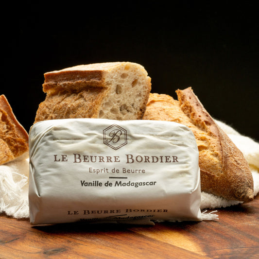 Le Beurre Bordier Vanille de Madagascar butter in branded wrapper on wooden board with rustic sourdough bread, dark background