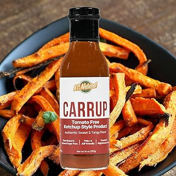 Bottle of KC Natural Carrup tomato-free ketchup style product on a plate of sweet potato fries.
