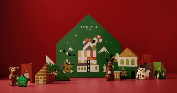 Läderach green Advent Calendar House with chocolate figures and festive boxes on a red background
