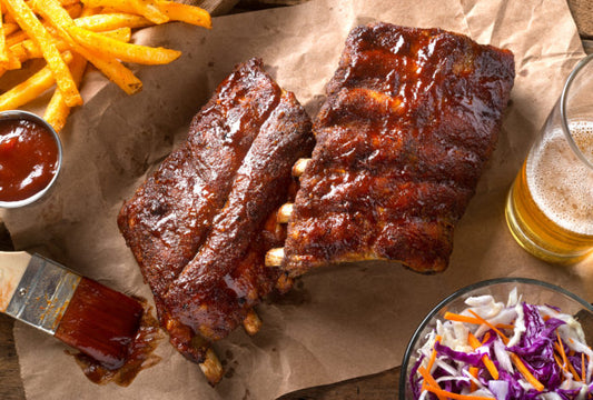 Barbecue ribs with fries, coleslaw, and a beer on brown paper