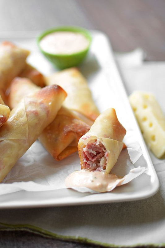 Spring rolls with a filling on a white plate with a small bowl of dipping sauce.
