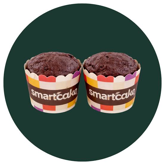 Two chocolate cupcakes in branded paper liners with a colorful scalloped edge, set against a dark green circular background on a white canvas.