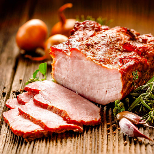 Sliced roasted pork with herbs and onions on a wooden surface